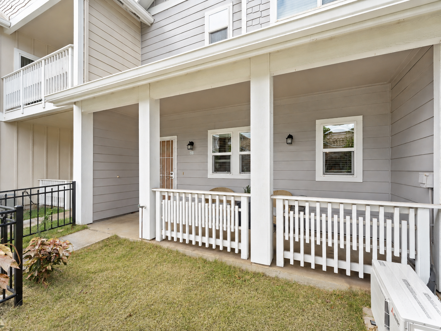 Covered front lanai with railing and fenced grass yard