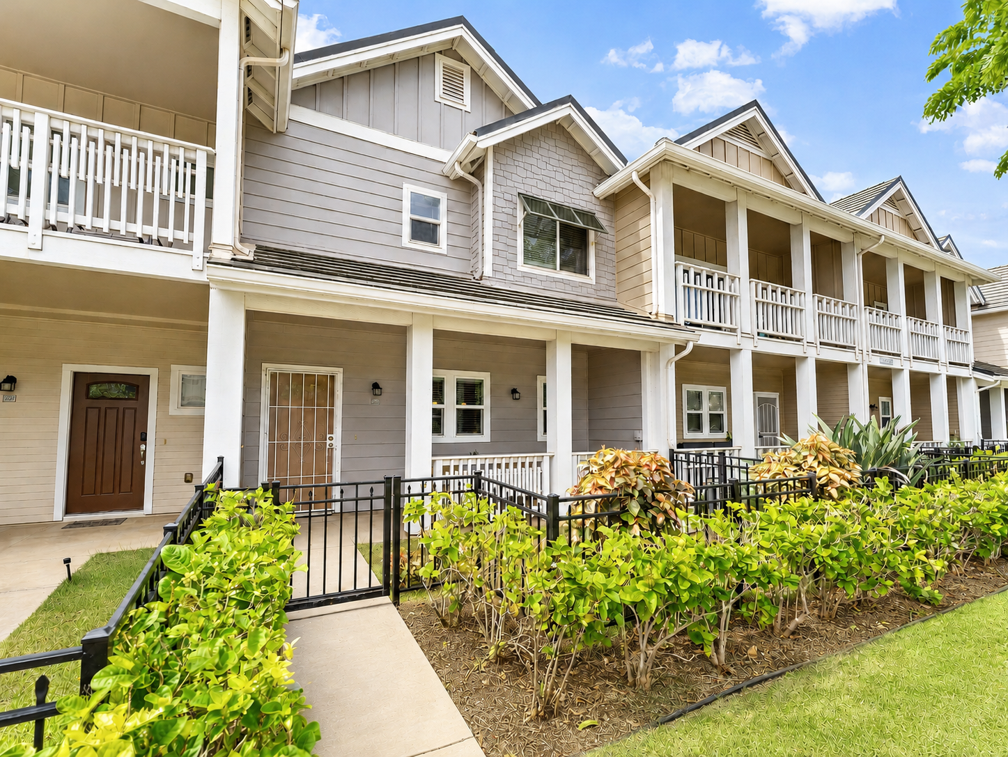 Walkway to the front entry with fenced landscaping and upper balcony